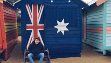 Ignacio seated in front of a cabin which has a painted Australian flag