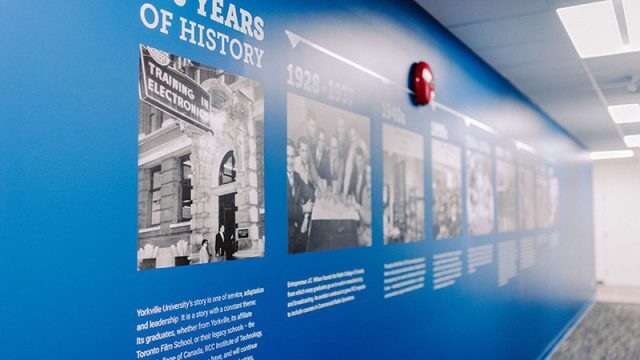 Yorkville University - Blue wall with images and text that showcases the 100 years of history of the university