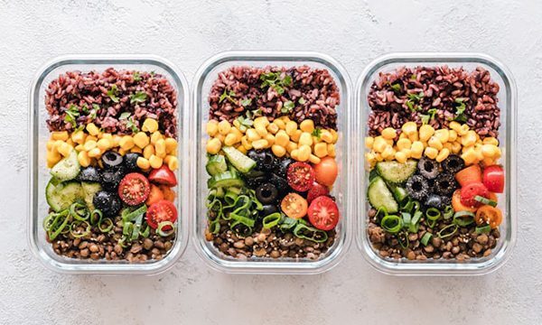 Three food containers containing prepared meals of grains and vegetables.