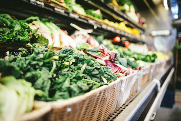 A wall chiller filled with produce inside a grocery store.
