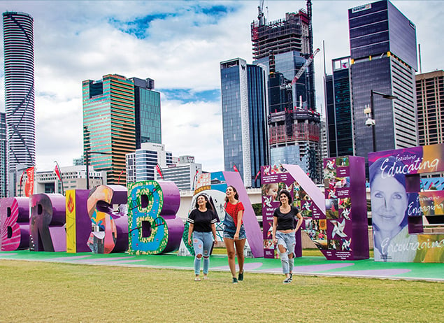 English students from ILSC Brisbane language school walk in front of the Brisbane sign during activities
