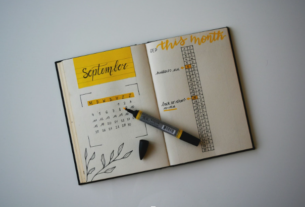 A bullet journal open to a September spread, featuring a calendar, tasks, and a black marker resting on the page.
