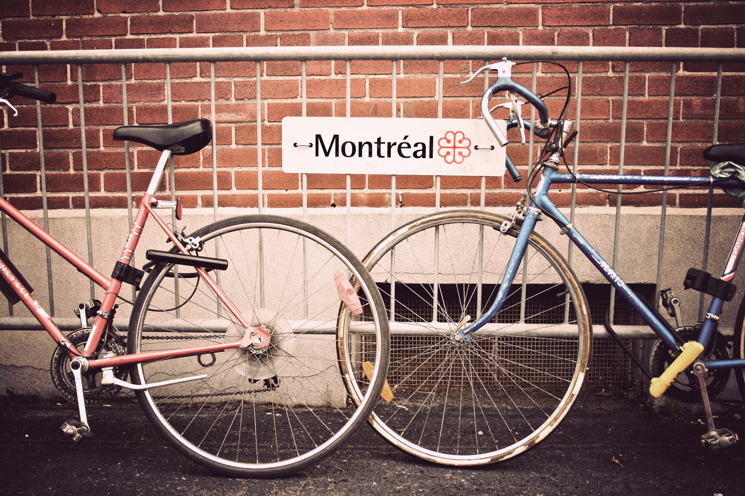 Two bicycles lean against a metal railing with a 