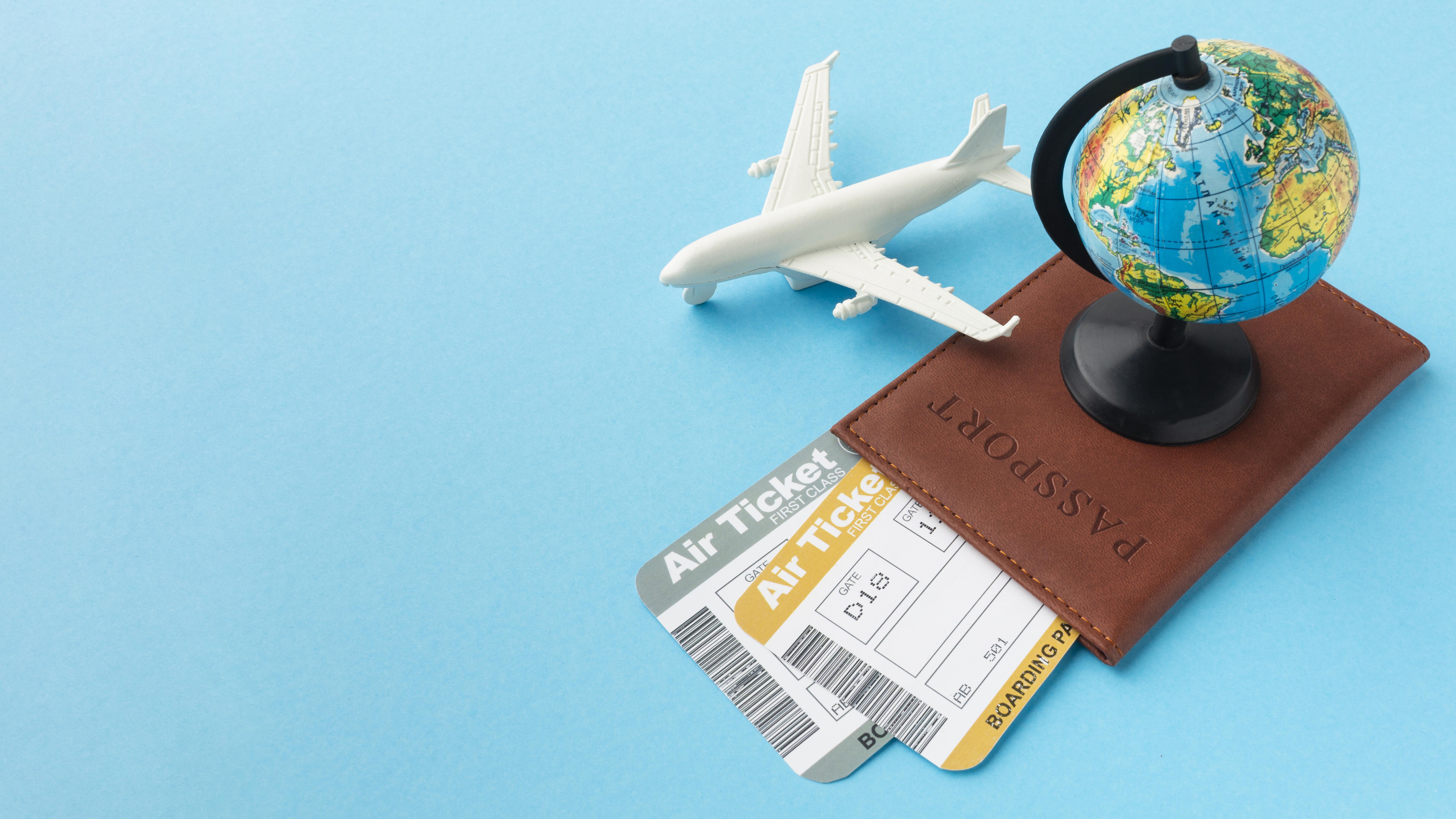 A small globe and toy plane rest on a passport with airline tickets, set against a blue background. The scene suggests travel and adventure.