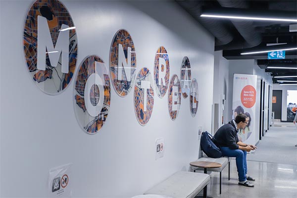 College Greystone in Montreal campus with student sitting beside Montreal sign.  Work and study in Montreal in a practicum program at our career college.