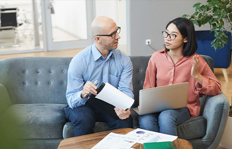 International student with boss sitting on couch discussing business files. Work in Canada in a Greystone College co-op program