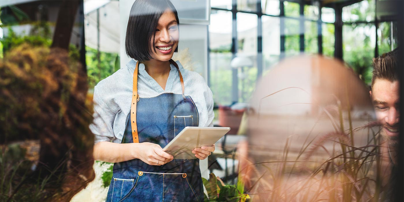 Woman working as a server, taking orders in a restaurant.  Study hospitality at a career college in Canada, in Toronto or Vancouver