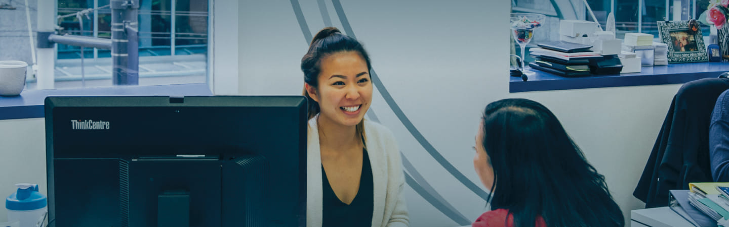 Greystone College female staff person sitting behind desk talking with a female student. Learn about policies at Greystone College in Canada