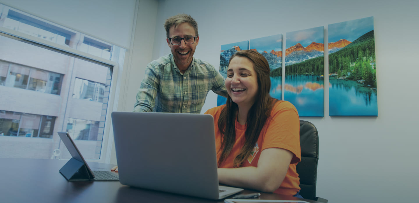 female international student working in an office with boss overseeing her work.  Work in Canada as a student through co-op, off campus work, or practicum experience