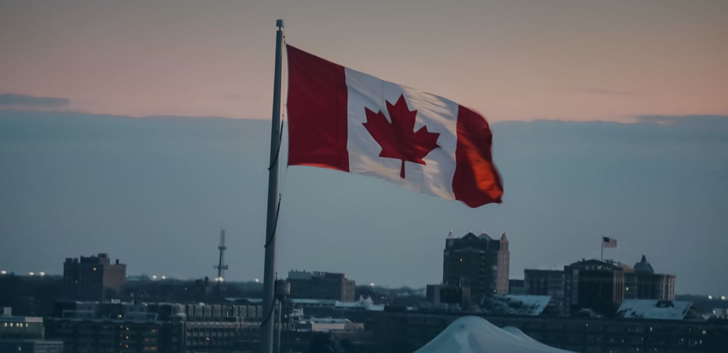 Canada flag above a city.  Get visa and immigration consulting to help you with visa and permit applications in Canada.