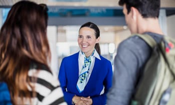 Hotel concierge greets 2 travelers, work while you study hospitality at Greystone College, a career college in Canada with co-op programs